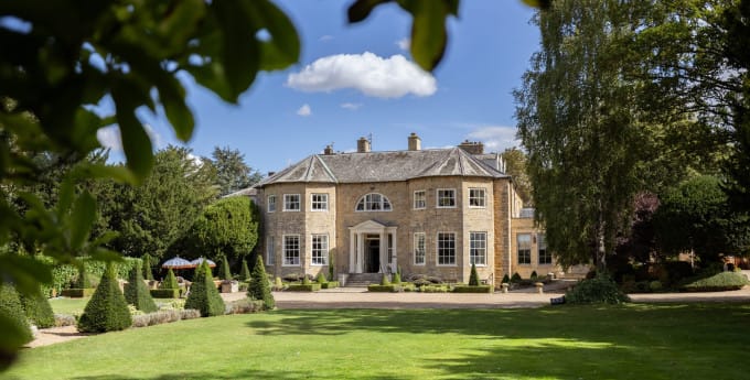 Washingborough Hall Hotel, a grand Georgian manor with curved wings and a columned entrance, set among lawns, trees, and neatly clipped topiary.