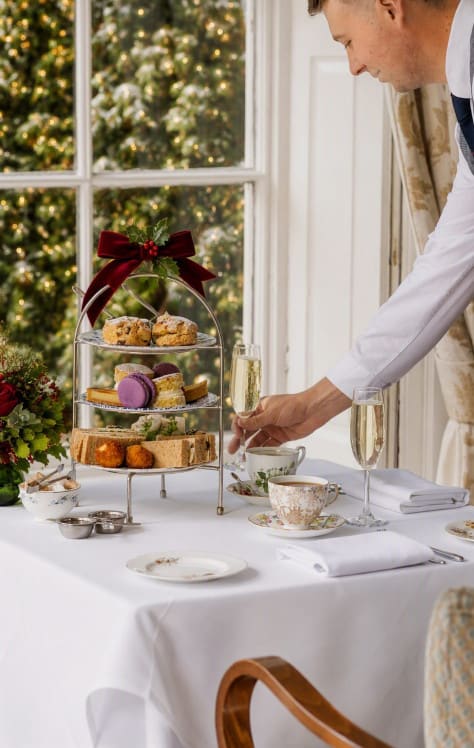 Luxury festive afternoon tea at Washingborough Hall with seasonal flowers, festive bow, sparkling lights and traditional afternoon tea service.