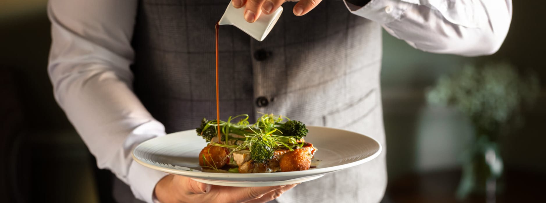 Boxing Day lunch at Washingborough Hall with a chef pouring rich gravy over an elegantly plated seasonal dish in a warm dining setting.
