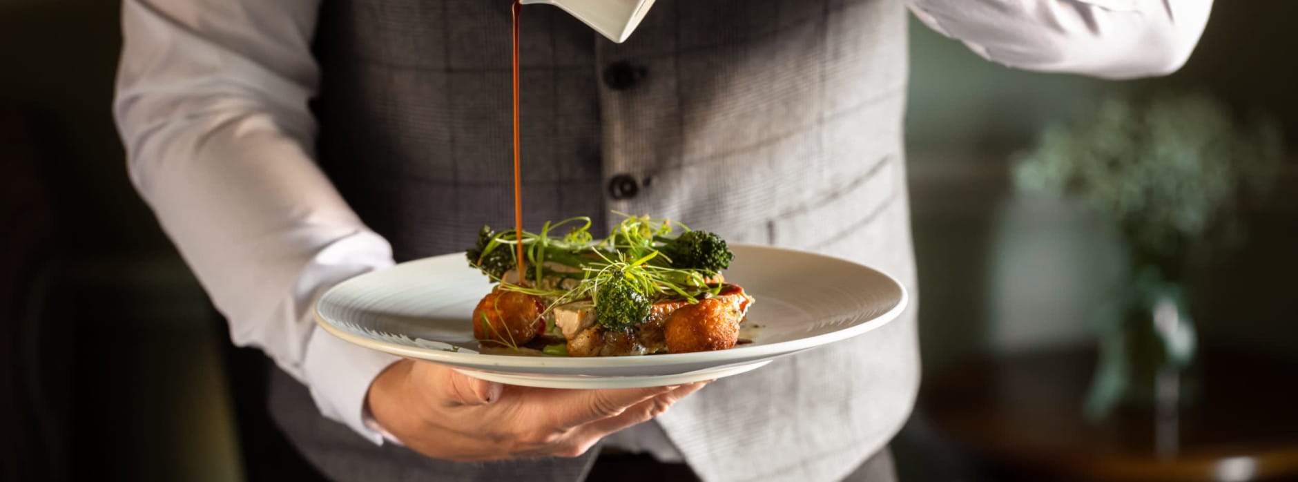 Boxing Day lunch at Washingborough Hall with a chef pouring rich gravy over an elegantly plated seasonal dish in a warm dining setting.