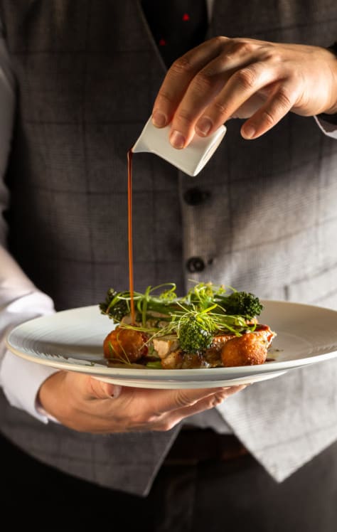 Boxing Day lunch at Washingborough Hall with a chef pouring rich gravy over an elegantly plated seasonal dish in a warm dining setting.