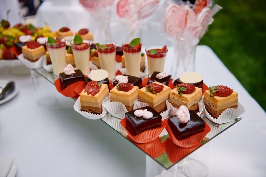 A dessert table with an elegant display of layered cakes, chocolate pastries, panna cotta, and strawberry-topped treats, beautifully arranged in individual servings.
